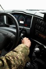 A military man in camouflage is using a key to start a large diesel fueling truck.