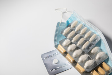medical mask with tablets lying on a light background.