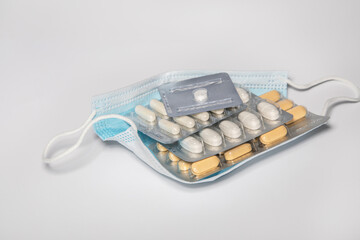 Protective medical mask on which lie the plates of various tablets.