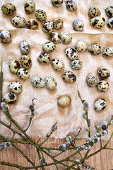 top view of quail eggs and willow branches in beige on linen towel, Easter background