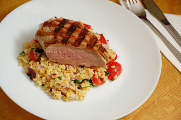 Pork tenderloin on bulgur salad on plate