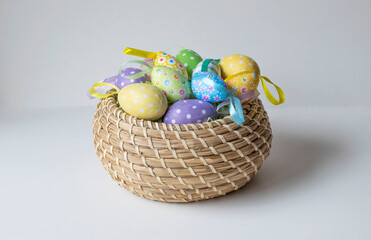 Colorful Easter eggs in a brown wicker basket on a white background. Easter