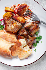 A plate with the remains of a pork kebab, there are no people.