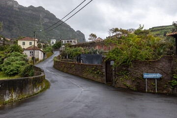 Fototapeta premium Deserted paved road through a Portuguese village on the island of Madeira with a signpost to a viewpoint
