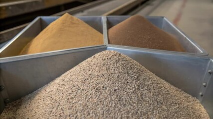 A medium closeup of abrasive media piling in a storage hopper with differentsized grains clearly visible indicating the variety used in the sandblasting process.