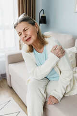 Vertical indoor image of senior lady in casual clothes suffering terrible unbearable pain in upper...