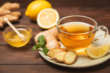 Cup of hot ginger tea with slices of ginger root on wooden background. Warming drink. Alternative medicine. Tea with honey, lemon, ginger and mint. Space for text. Copy space