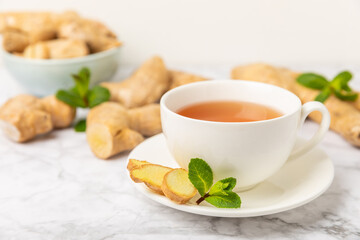 Cup of hot ginger tea with slices of ginger root on wooden background. Warming drink. Alternative medicine. Tea with honey, lemon, ginger and mint. Space for text. Copy space