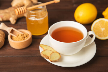 Cup of hot ginger tea with slices of ginger root on wooden background. Warming drink. Alternative medicine. Tea with honey, lemon, ginger and mint. Space for text. Copy space