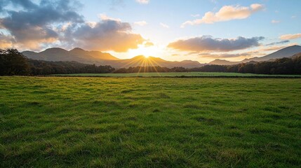 Obraz premium A picturesque landscape featuring lush green fields and majestic mountains, illuminated by a stunning sunset.