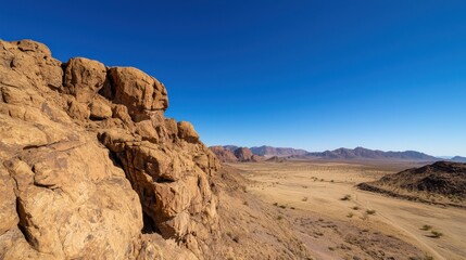 Fototapeta premium A stunning view of a rocky landscape under a clear blue sky, showcasing the natural beauty of arid terrain and distant mountains.
