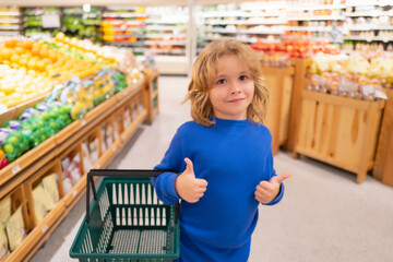 Child with shopping basket. Kid on shopping in supermarket. Child with shopping basket. Grocery store, choosing goods. Shopping for healthy.
