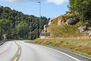A road with a yellow line and a sign on the side in Norway