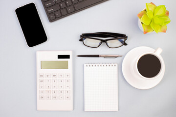 Tablet, calculator, phone, pen and a cup of coffee, lot of things on a light background. Top view with copy space.