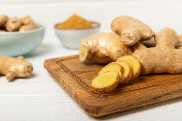 Fototapeta premium Fresh ginger on wooden background. Dry ginger. Sliced ​​ginger with honey and lemon. Ginger root. Traditional alternative medicine, healing tea for immunity. Seasoning and spices concept. Copy space.