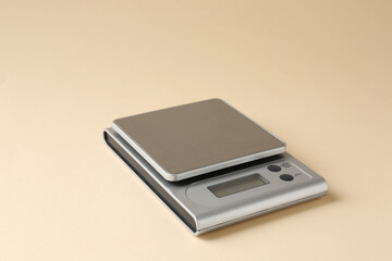 Modern electronic kitchen scale on beige background, closeup
