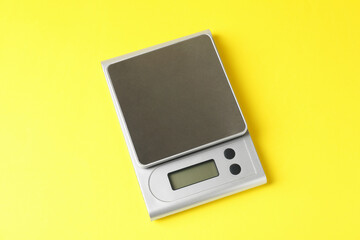 Modern electronic kitchen scale on yellow background, above view