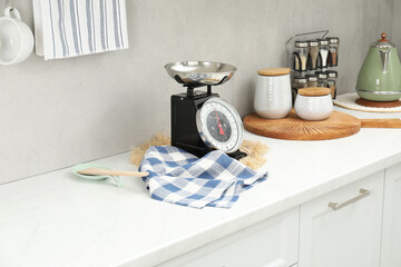 Retro mechanical kitchen scale and other utensils on white marble countertop indoors