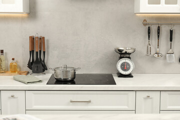 Retro mechanical kitchen scale, other utensils and oils on white countertop indoors