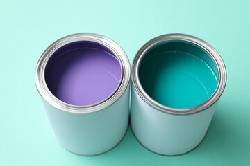 Can of different paints on turquoise background, closeup