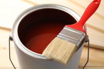 Can of red paint and brush on table, closeup