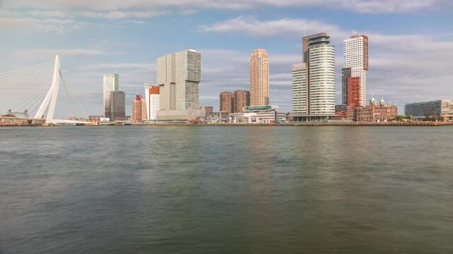 Panorama showing Rotterdam skyline timelapse from Nieuwe Maas River bank to Wilhelminapier and Kop van Zuid. Modern skyscrapers, ship terminal and Erasmus Bridge, waterfront with boats passing by