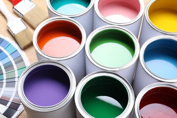 Cans of bright paints, brushes and color palettes on table