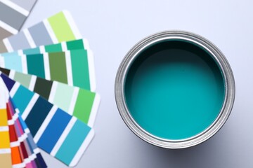 Can of bright paint and color palettes on light grey background, flat lay
