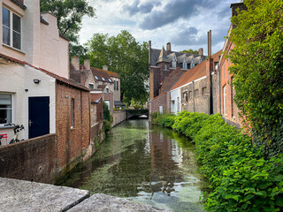 View of one of the many canals in the city of Bruges, with its typical medieval houses on each bank, during a quiet summer in 2023