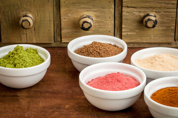 super fruit and leaf powders in small ceramic bowls - baobab, noni, yumberry, moringa, mangosteen