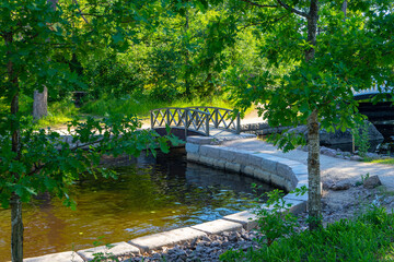 Fototapeta premium Pedestrian paths and a wooden bridge over a canal in Monrepos Park in Vyborg