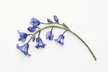 Fototapeta premium Intricate embroidery depicting a delicate sprig of bluebells, showcasing artistry and detail.