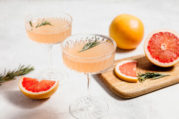 Elegant grapefruit and rosemary cocktails served in crystal glasses with fresh grapefruit slices, set against a light background. Perfect for summer gatherings and holiday party. Refreshing mocktail.