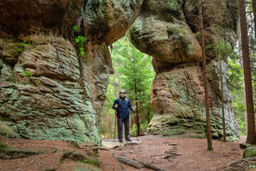 Man posing on natural stone gate called Wrota in Skalne Grzyby rocks in Stolowe Mountains National Park, Poland