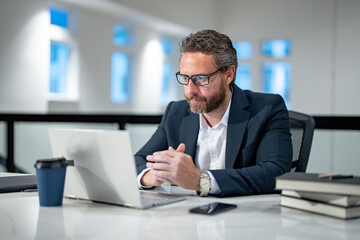 Obraz premium Handsome 40s business man working with laptop in office. Gray hair mature business man director using laptop. Millennial manager at office workplace. Ceo office workers business people at office.