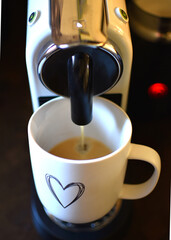 coffee machine and espresso coffee in a white mug with hearts