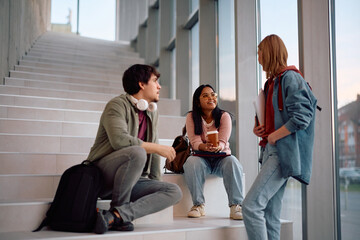 Happy Indian student talking to her university friends while relaxing at campus.