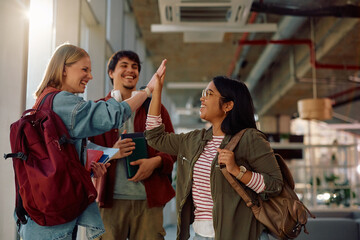 Cheerful female friends giving high-five at university.