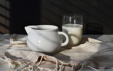Milk in a glass and a white milk jug on a black background.