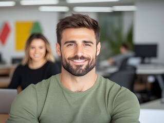 Fototapeta premium Bearded man with folded arms in casual green shirt standing in modern tech workspace showing confidence digital thinking focus and professional strength