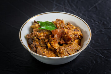 Beef masala or roast, Kerala-style homemade recipe, garnished with curry leaves and served in a white bowl against a black background.
