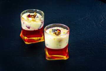 Jelly sweet dessert with white milky, red and pink layers isolated on black background. Front closeup view of fresh served