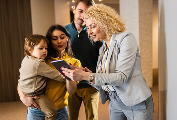 Saleswoman showing a young couple with a child the panels for decorating the interior of the home.