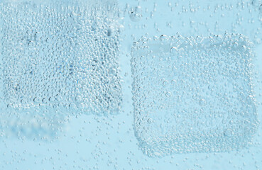 Refreshing soda water with ice cubes in glass against light blue background, closeup