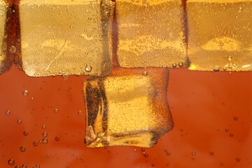 Refreshing soda water with ice cubes as background, closeup