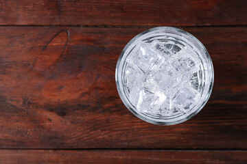 Refreshing soda water with ice cubes in glass on wooden table, top view. Space for text