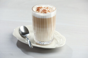 Tasty latte macchiato in glass on white table, closeup. Coffee drink