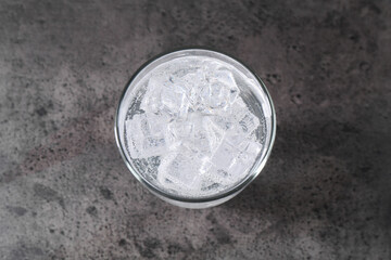Refreshing soda water with ice cubes in glass on grey table, top view