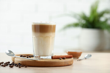 Tasty latte macchiato in glass on wooden table, space for text