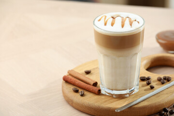 Tasty latte macchiato in glass on wooden table, closeup. Space for text